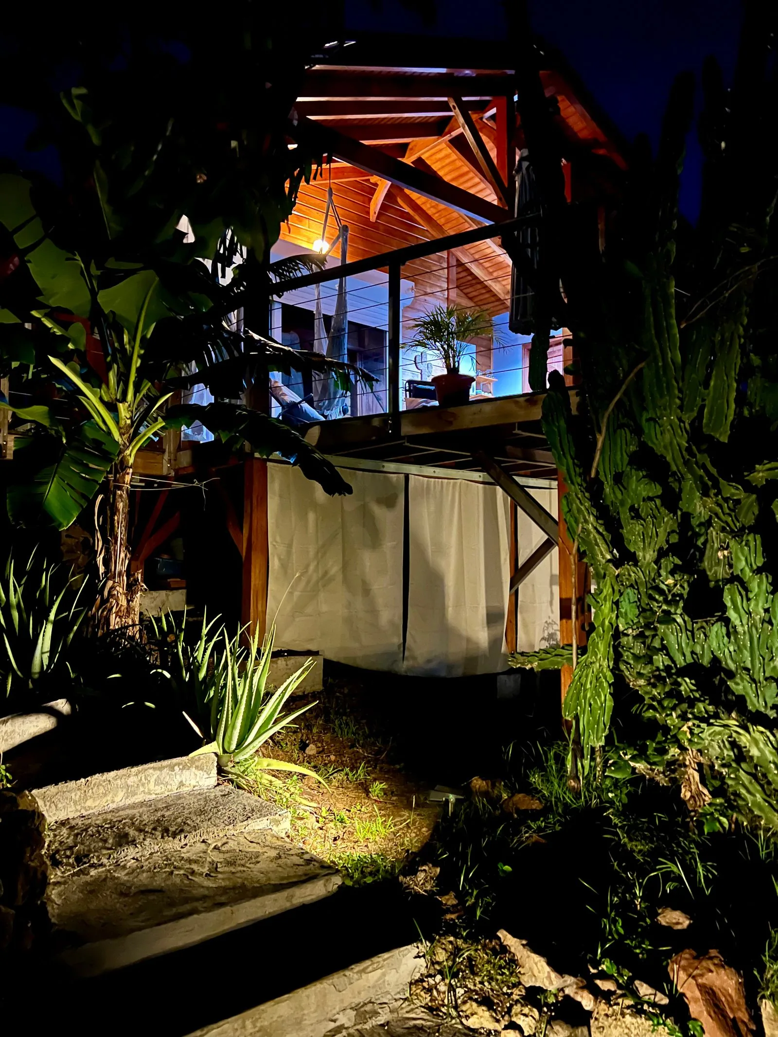 Bungalow Panorama Kreyòl sur pilotis illuminé la nuit, vue latérale