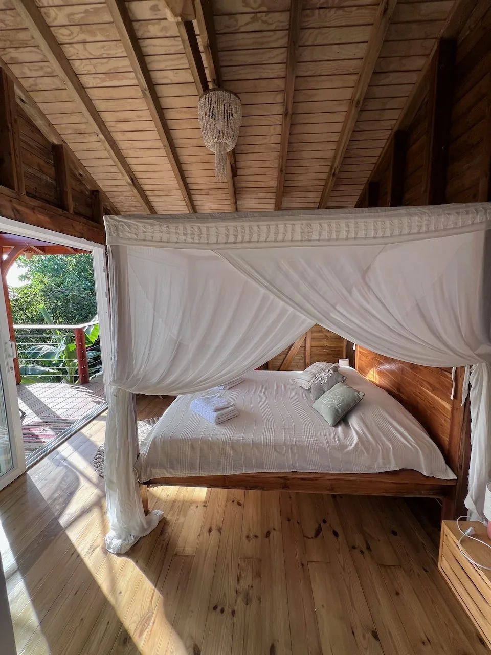 Chambre avec lit à baldaquin sous charpente en bois de style créole