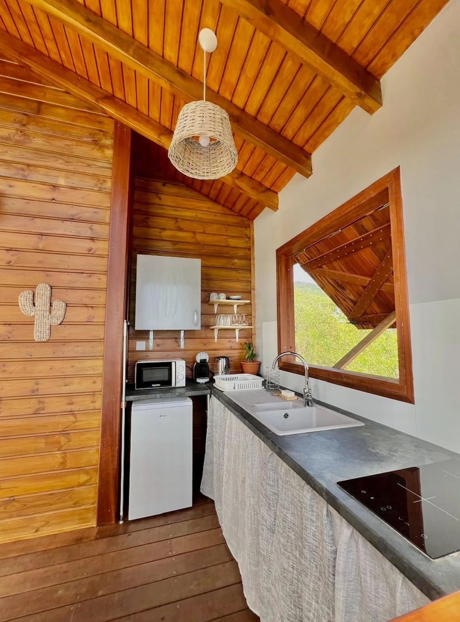 Cuisine intérieure avec plan de travail en béton et plafond en bois sous charpente créole