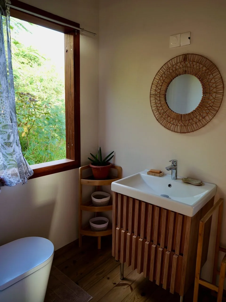 Salle de bain avec miroir en rotin, ambiance naturelle et chaleureuse