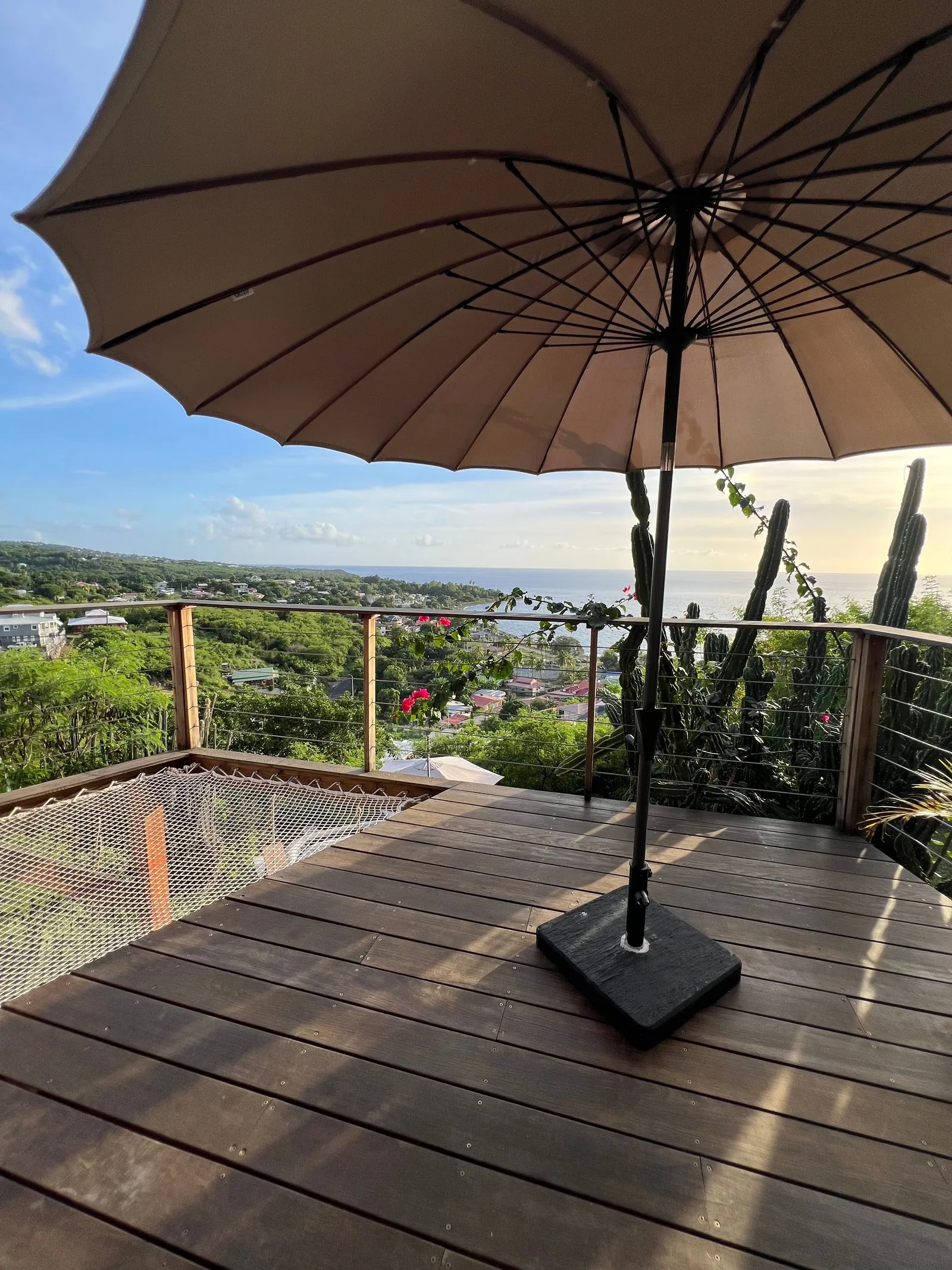 Terrasse en bois avec parasol, vue sur la ville et la mer en journée